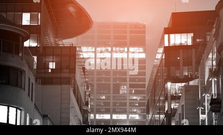 Pattern of office buildings windows illuminated at night. Lighting with Glass architecture facade design with reflection in urban. Black and white. Stock Photo