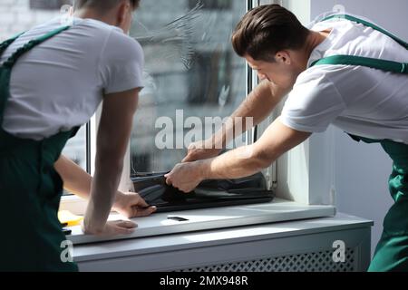 Professional workers tinting window with foil indoors Stock Photo