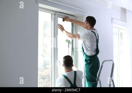 Professional workers tinting window with foil indoors Stock Photo