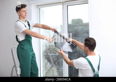 Professional workers tinting window with foil indoors Stock Photo