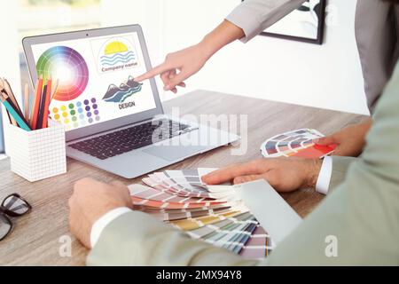 Professional designers working with color palette samples at desk at office table, closeup Stock Photo