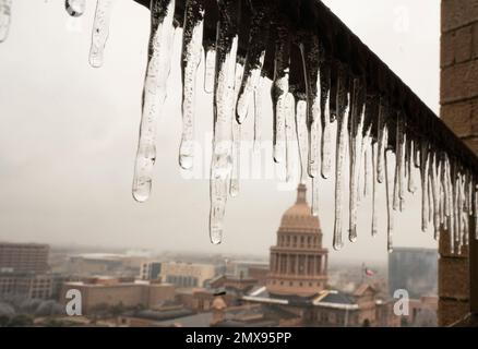 Austin Texas USA, February 1 2023: Icicles drip from a balcony with the Texas Capitol in the background as Austin and central Texas recover from an ice storm that knocked out power to thousands and caused tree damage throughout the city. About a third of Austin is without power two days after the storm hit. Credit: Bob Daemmrich/Alamy Live News Stock Photo