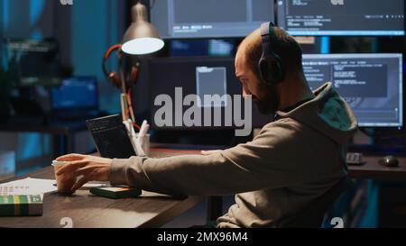 IT coder taking supplements out of box in office, using vitamins pills to work late at night. Engineer programming cloud computing app code on terminal window, using medicine drugs. Stock Photo