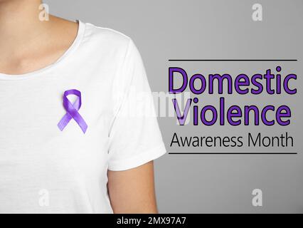 Woman with purple ribbon on grey background, closeup. Symbol of Domestic Violence Awareness Stock Photo