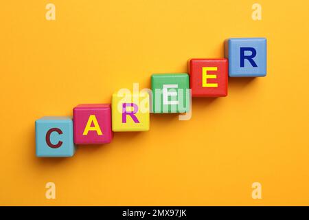 Colorful cubes with word CAREER on orange background, flat lay Stock Photo