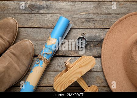 Compass with world map, shoes, toy airplane and hat on wooden background Stock Photo