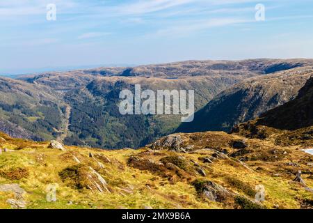 People sitting on rocks looking at a scenic view from the top of Ulriken Mountain in Bergen, Norway Stock Photo