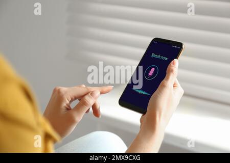 Woman using voice search on smartphone indoors, closeup Stock Photo