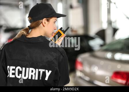 Security guard using portable radio transmitter in automobile repair shop, space for text Stock Photo