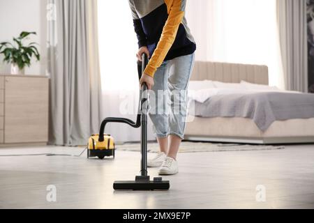 Young woman using vacuum cleaner at home, closeup Stock Photo