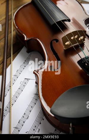 Beautiful violin, bow and note sheets on wooden table Stock Photo