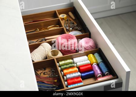 Sewing accessories in open desk drawer indoors Stock Photo