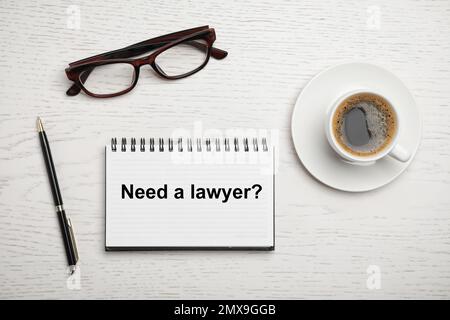 Flat lay composition with text NEED A LAWYER? written in notepad on white wooden table Stock Photo