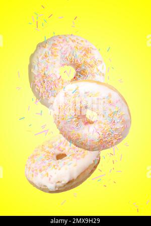 Set of falling delicious donuts on yellow background Stock Photo