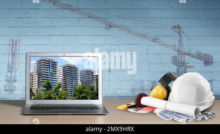 Modern laptop with engineer equipment on table and construction crane. Double exposure Stock Photo