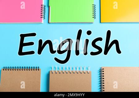Flat lay composition with notebooks on light blue background. Learning English Stock Photo