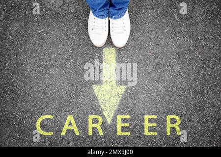 Woman standing near arrow on asphalt, top view. Career choice concept Stock Photo