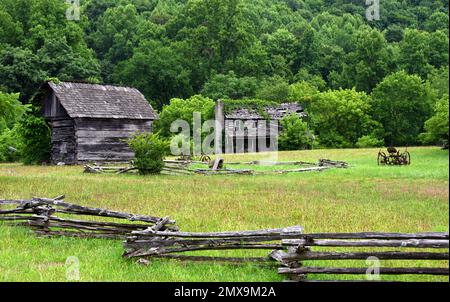 Splitrail fence fronts the 1800s Homeplace Mountain Farm and Museum in Southwest Virginia.  Ruins of two story log cabin home stands at back of proper Stock Photo