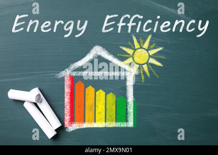 Energy efficiency concept. Pieces of chalk and house drawn on chalkboard Stock Photo