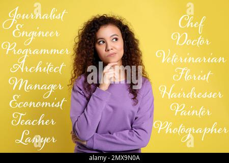 Thoughtful African American woman choosing profession on yellow background Stock Photo