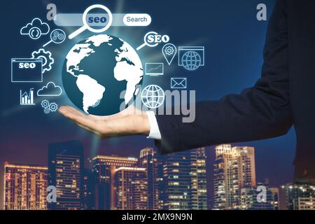 Man demonstrating directions of SEO. World globe with icons of keyword research, customization and others Stock Photo