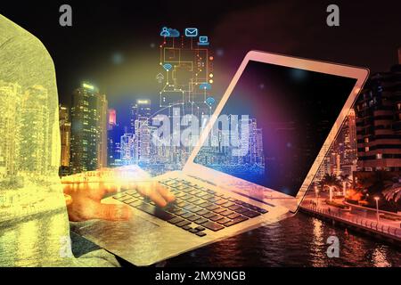 Young man with laptop and virtual image of city, closeup. Modern technology Stock Photo