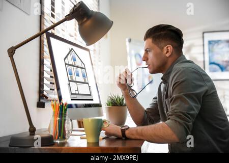 Engineer at work. Man projecting house in office Stock Photo