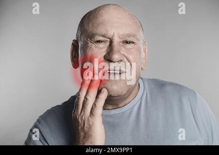 Senior man suffering from toothache on grey background Stock Photo