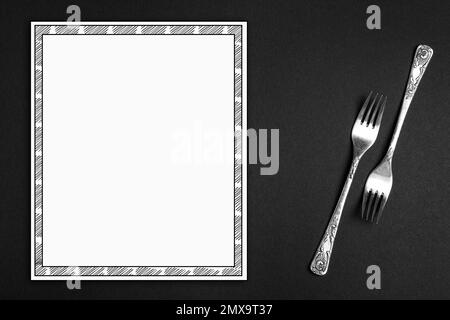 Silver forks and empty menu on black background, flat lay. Space for text Stock Photo