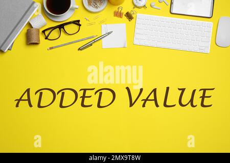 Added value concept. Flat lay composition with computer accessories and different office items on yellow background Stock Photo