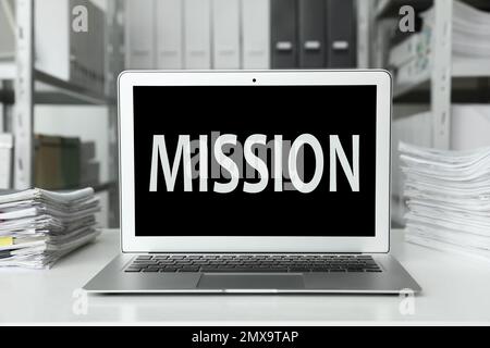 Modern laptop with word MISSION on screen indoors Stock Photo