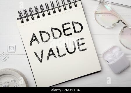 Added value concept. Flat lay composition with stationery on white wooden table Stock Photo