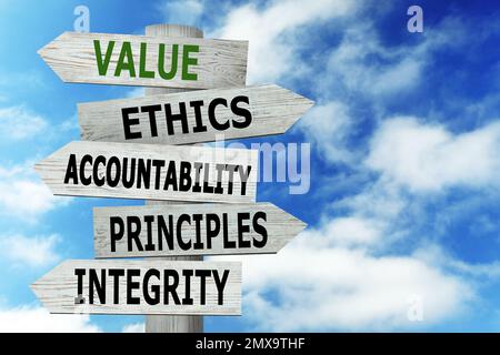 Moral values concept. Wooden signpost with different directions against blue sky Stock Photo