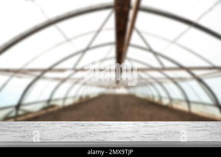 Empty stone surface and blurred view of large agricultural greenhouse. Space for text Stock Photo