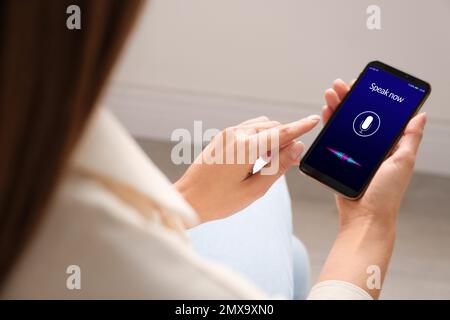 Woman using voice search on smartphone indoors, closeup Stock Photo