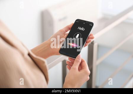 Woman using voice search on smartphone indoors, closeup Stock Photo