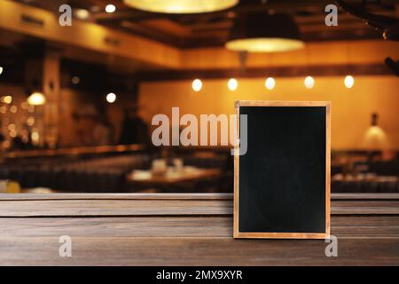 Blank small blackboard on wooden table in cafe, mockup for menu design Stock Photo