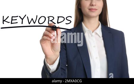 Woman writing word KEYWORDS on transparent board against white background, closeup Stock Photo