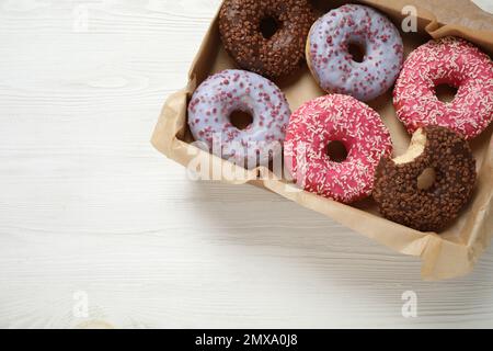 Delicious glazed donuts on white wooden table, top view. Space for text Stock Photo