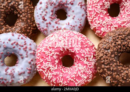 Delicious glazed donuts on parchment paper, closeup. Sweet pastries Stock Photo