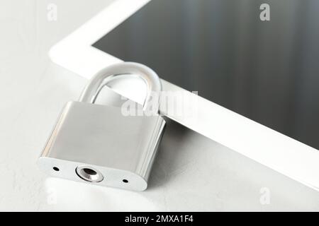 Metal lock and tablet on light grey table, closeup. Protection from cyber attack Stock Photo