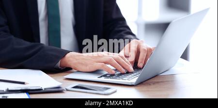 Man working on computer at table in office, closeup. Banner design Stock Photo