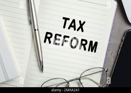 Notebook with words TAX REFORM, pen and glasses on table, closeup Stock Photo