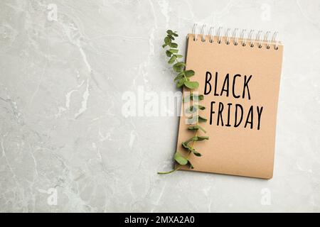 Stylish notebook with text BLACK FRIDAY and eucalyptus on grey marble table, top view. Space for design Stock Photo