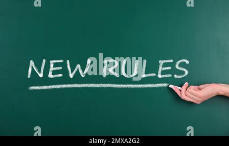 Woman writing text NEW RULES on chalkboard, closeup Stock Photo