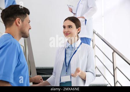 Female doctor talking to colleague on staircase in clinic Stock Photo