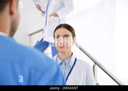 Female doctor talking to colleague on staircase in clinic Stock Photo