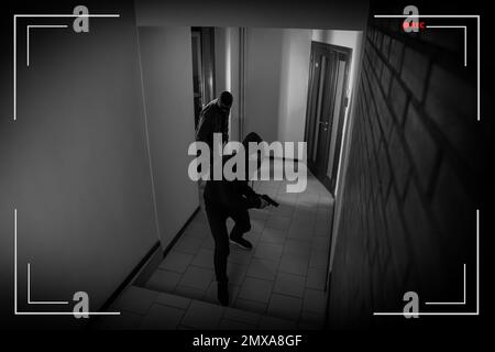 Dangerous criminals in masks with weapon in hallway, view through CCTV camera Stock Photo