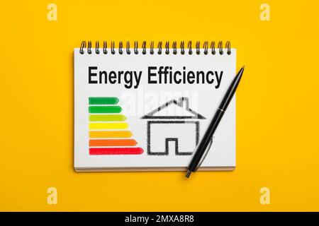 Energy efficiency concept. Notebook with drawn house and chart on yellow background, top view Stock Photo