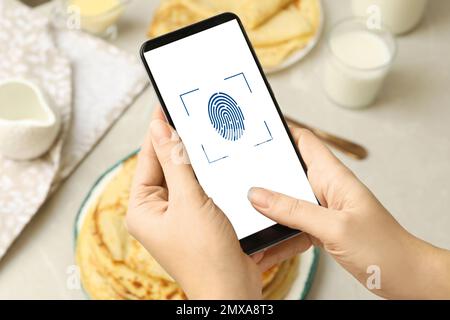 Woman scanning fingerprint on smartphone indoors, closeup. Digital identity Stock Photo